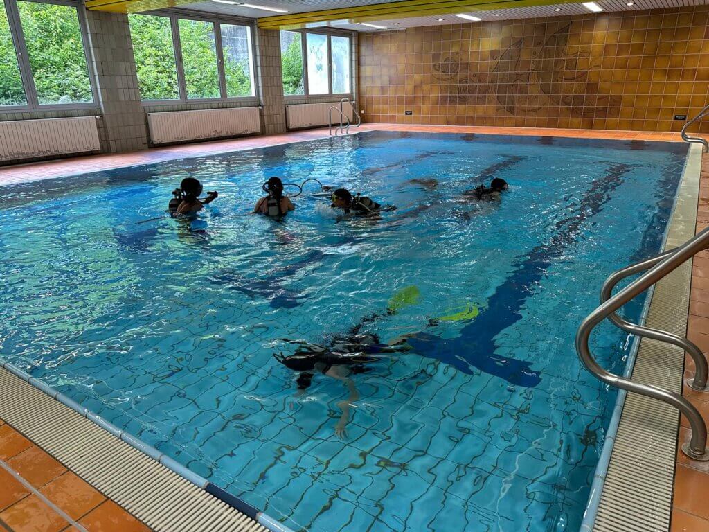 Ein Schwimmbad mit 5 Kindern in Taucherausrüstung unter Wasser